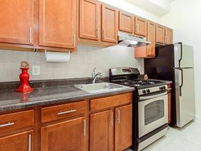Washington apartment for rent - a kitchen with wooden cabinets and stainless steel appliances at the calverton apartment building in washington dc