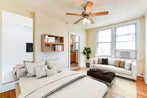 Washington apartment for rent - studio apartment showing sofa, bed, ceiling fan, large windows and view of kitchen at the foreland apartments in washinton dc