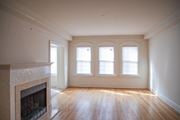 Pikesville apartment for rent - A large empty room with a fireplace and wooden floors.