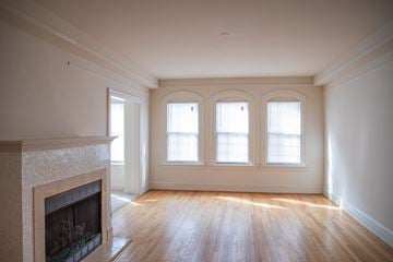 Pikesville apartment for rent - A large empty room with a fireplace and wooden floors.