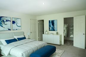 Owings Mills apartment for rent - A bedroom with a large bed and a dresser with a mirror at Cascades Overlook Apts., Owings Mills