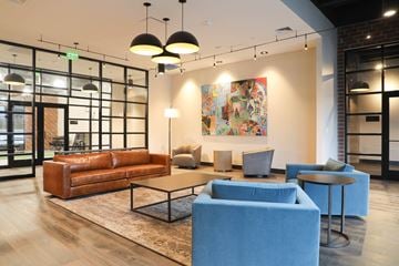 Owings Mills apartment for rent - A modern living room with a large painting on the wall and a brown leather couch.