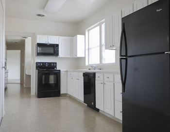 A kitchen with white cabinets and black appliances