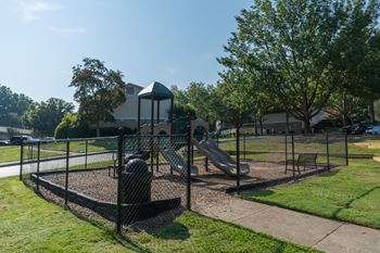 A playground with two slides and a swing set in a park