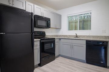 Atlanta apartment for rent - A black refrigerator stands in a kitchen with a black oven and microwave.