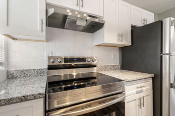 A modern kitchen with a stainless steel oven and black refrigerator.