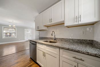 A kitchen with white cabinets and a granite countertop with sink