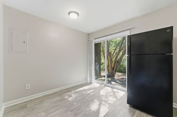 Atlanta apartment for rent - A black refrigerator is in a kitchen with a window that looks out to a tree.