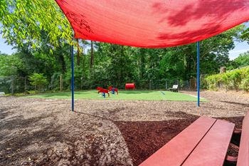 Two kids playing in a park under a red canopy