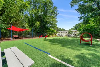 A park with a playground and kids playing in the grass