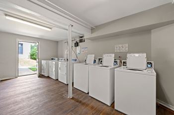 A row of washers and dryers in a room with a wood floor