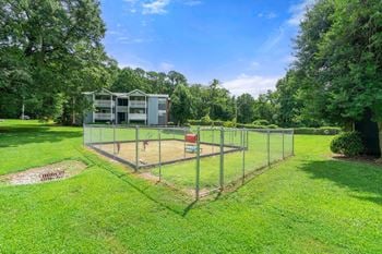 A fenced in dog park in the middle of a field