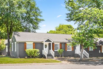 A grey house with red shutters and a white door.