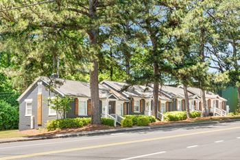 A row of houses with trees in front.