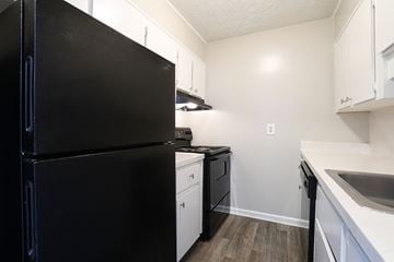 Lawrenceville apartment for rent - A black refrigerator is in a kitchen with white cabinets.