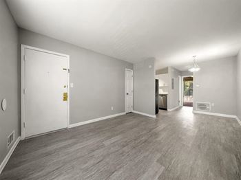 The living room and dining room of a house with a wood floor