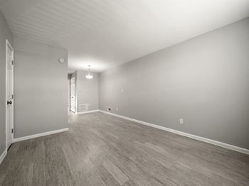 The living room and dining room of an empty house with wood flooring