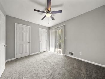 An empty living room with a ceiling fan and a window