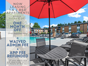 Smyrna apartment for rent - A red umbrella is in the foreground of a pool area with lounge chairs and a table.