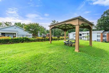 A gazebo with a picnic table in the grass