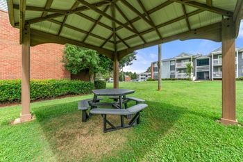 A picnic table sitting under a pavilion in the grass