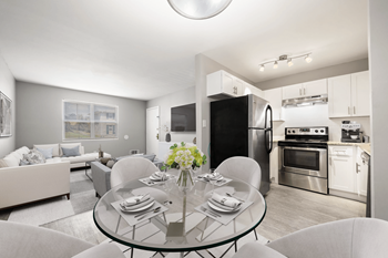 A living room with a glass table and a kitchen with stainless steel appliances