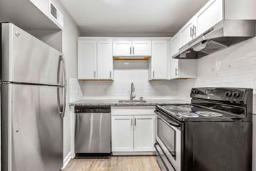 Sandy Springs apartment for rent - A kitchen with a stainless steel refrigerator and black stove.