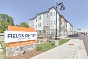 Longmont apartment for rent - A sign for Fields on 15th Apartment Homes stands in front of a building.