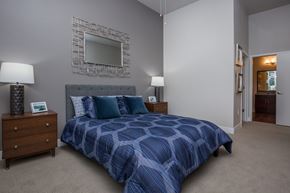 Arvada apartment for rent - A bedroom with a bed, nightstands, and a mirror on the wall.