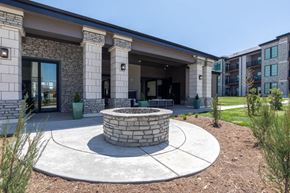Denver apartment for rent - A modern building with a stone pillar and a circular fire pit in front.
