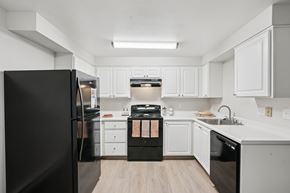 Vancouver apartment for rent - A black refrigerator is in a kitchen with white cabinets.