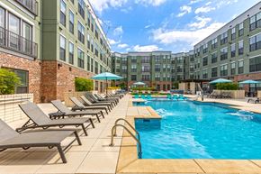 Chattanooga apartment for rent - A pool area with sun loungers and umbrellas in front of a building.