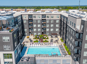 Kansas City apartment for rent - A large swimming pool is surrounded by lounge chairs in the middle of a courtyard.