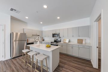 Phoenix apartment for rent - a kitchen with white cabinets and a white island with three stools