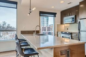 Denver apartment for rent - A kitchen with a long counter and a window overlooking a cityscape.