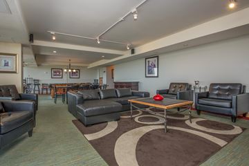 Denver apartment for rent - A living room with a brown rug and black leather furniture.