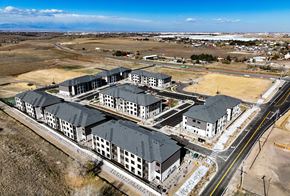 Aurora apartment for rent - A large building complex with a parking lot in front.