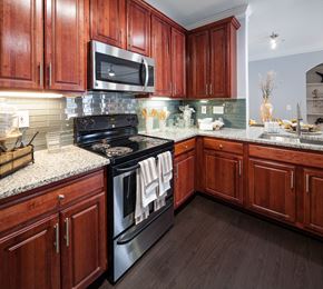 Lawrenceville apartment for rent - A kitchen with dark wood cabinets and a black stove top oven.