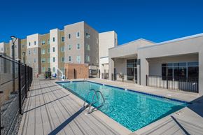 Rio Rancho apartment for rent - A swimming pool surrounded by a black fence and a building in the background.