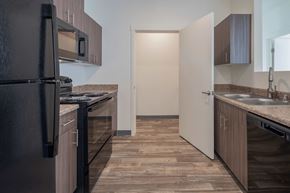 Rio Rancho apartment for rent - A kitchen with a black refrigerator and wooden flooring.