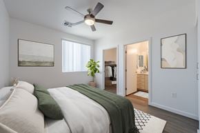 Phoenix apartment for rent - A bedroom with a bed, a ceiling fan, and a doorway leading to another room.