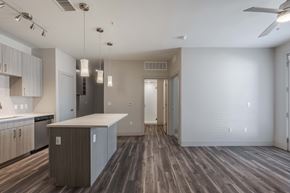 Denver apartment for rent - an empty living room with a kitchen and a ceiling fan