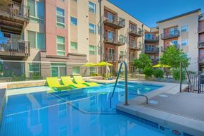 Arvada apartment for rent - A swimming pool with yellow sun loungers in front of apartment buildings.