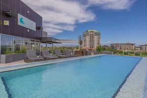 Denver apartment for rent - A swimming pool on a rooftop with chairs and a building in the background.