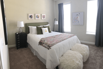 Gallatin apartment for rent - A bedroom with a large bed and a white fluffy ottoman.