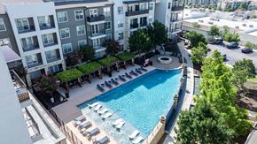 San Antonio apartment for rent - A swimming pool surrounded by lounge chairs and trees in a residential area.