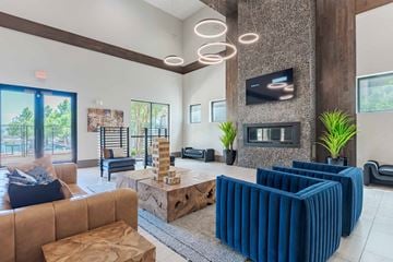 San Antonio apartment for rent - A living room with a brown couch, blue chairs, and a television mounted on the wall.