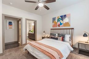 San Antonio apartment for rent - A bedroom with a bed, a ceiling fan, and a painting on the wall.
