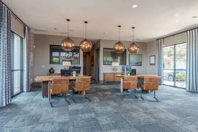 San Antonio apartment for rent - A modern office space with two desks and chairs, a table with a laptop, and a large window with curtains.