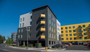 Vancouver apartment for rent - A modern multi-story building with a parking lot in front.
